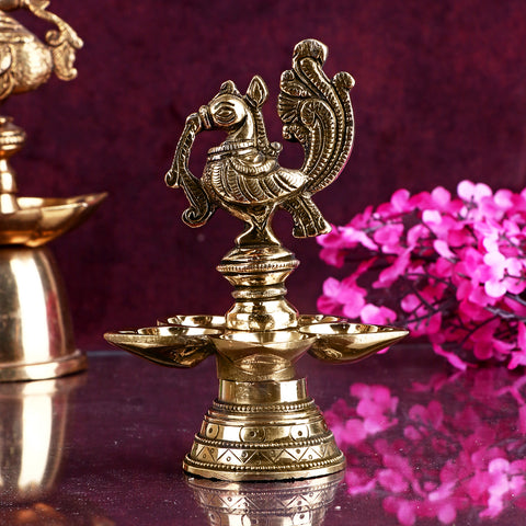 A beautifully crafted Peacock Panchmukhi Brass Diya, showcasing intricate peacock design with five flames. This traditional diya brings a touch of elegance and spirituality to your home or temple during religious ceremonies and festivals. India’s Largest Pooja Accessories Brand – www.satvikstore.in